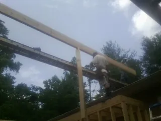 Carpenter setting a ridge beam over a new addition frame — Ice Dam Removal by Roofing Brothers in Mckenna