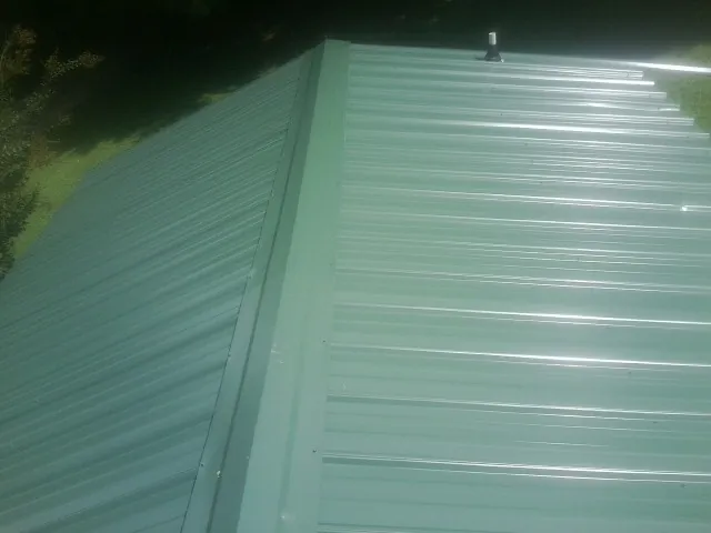 New green metal panels meeting at the ridge of a roof — Flat Roof Repair work by our crew in Mckenna