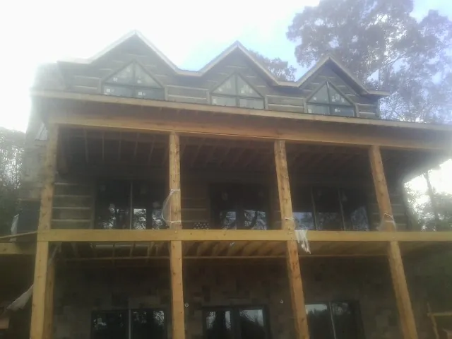 Dormers and porch framing on a large log home under construction — Roof Coating work by our crew in Mckenna