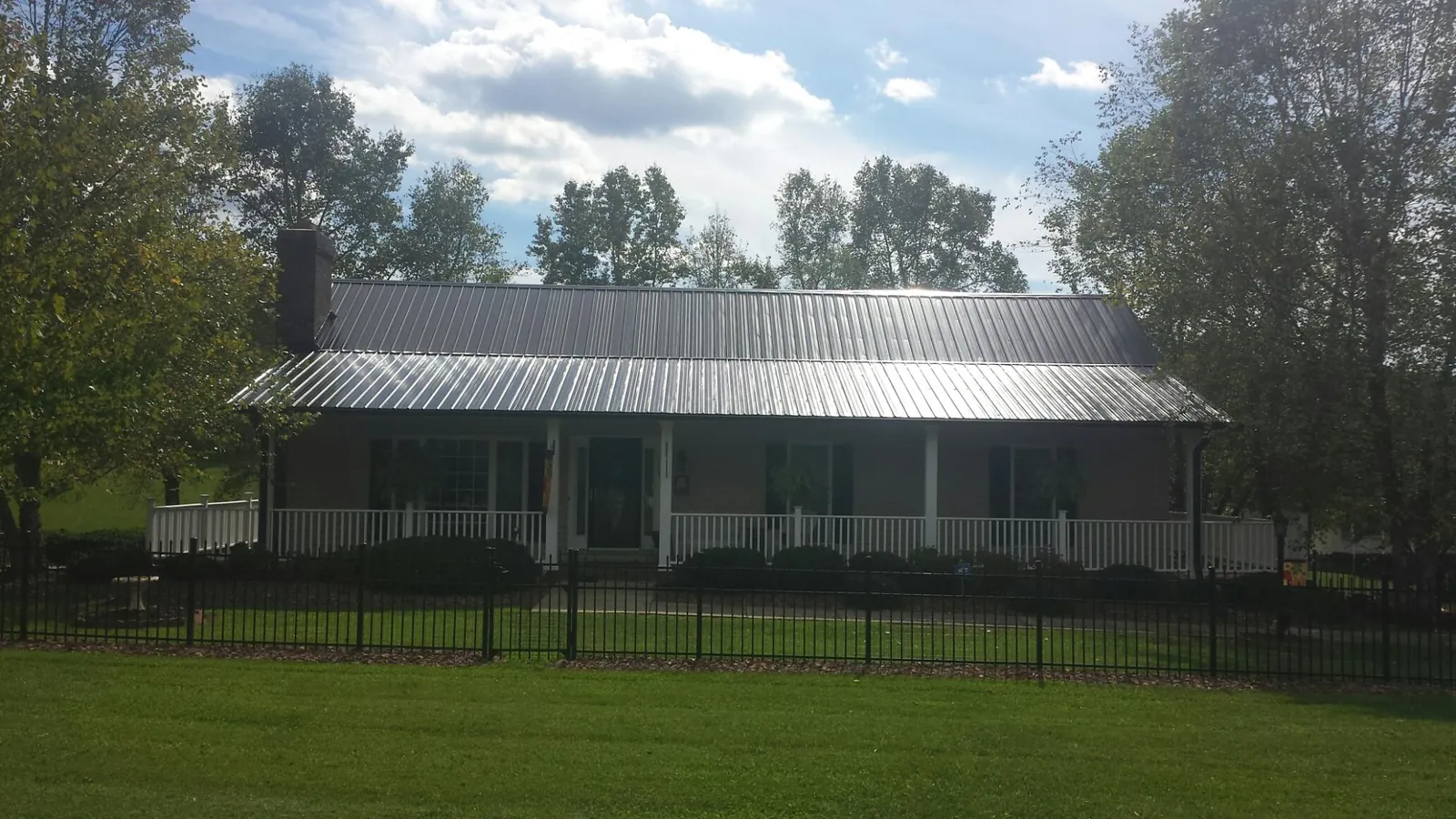 Gray metal roof on a brick ranch with a full width front porch — Gutter Guard Installation work by our crew in Mckenna