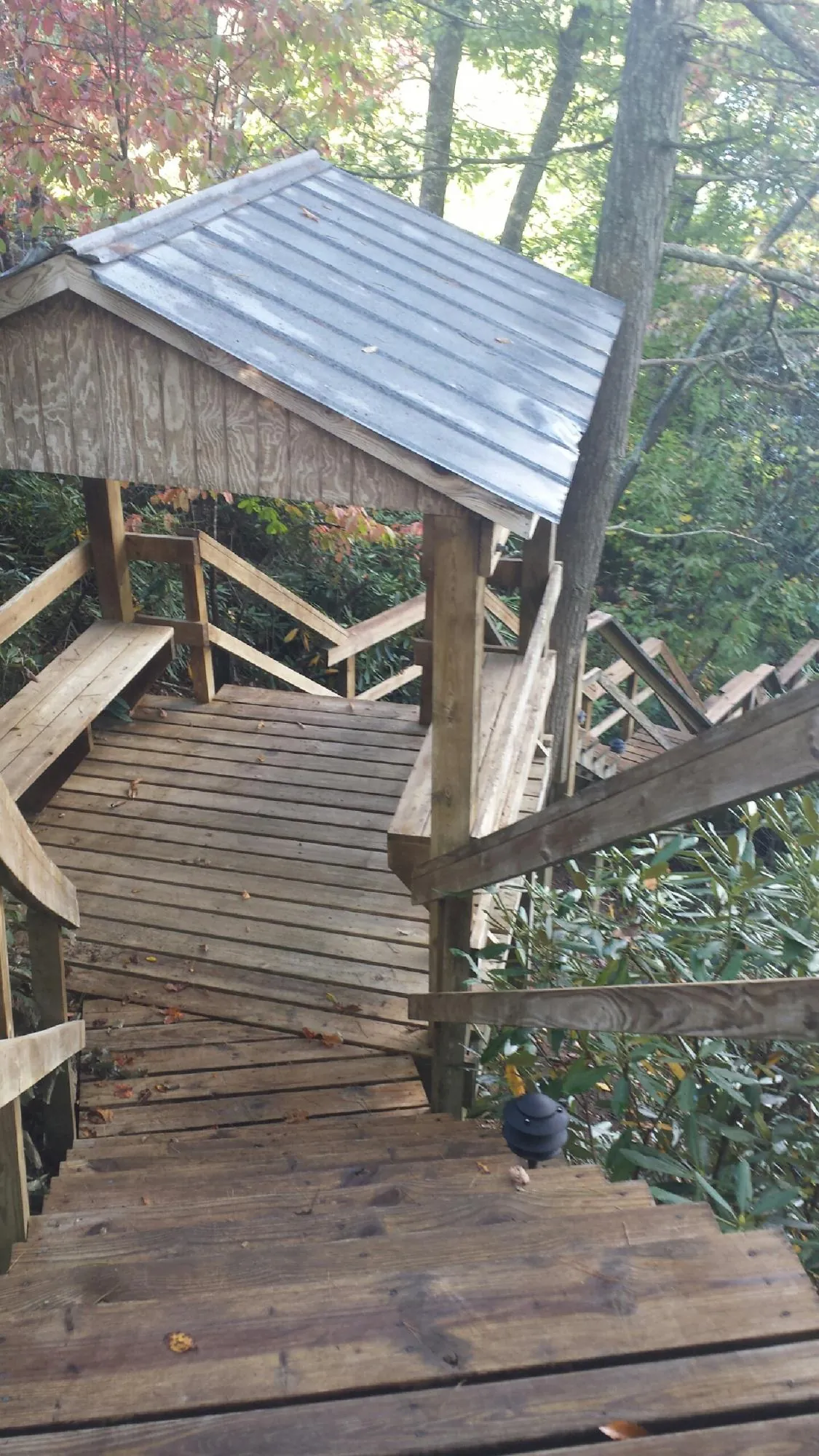 Metal roofed shelter over wooden steps on a wooded walkway — Skylight Repair & Installation work by our crew in Mckenna