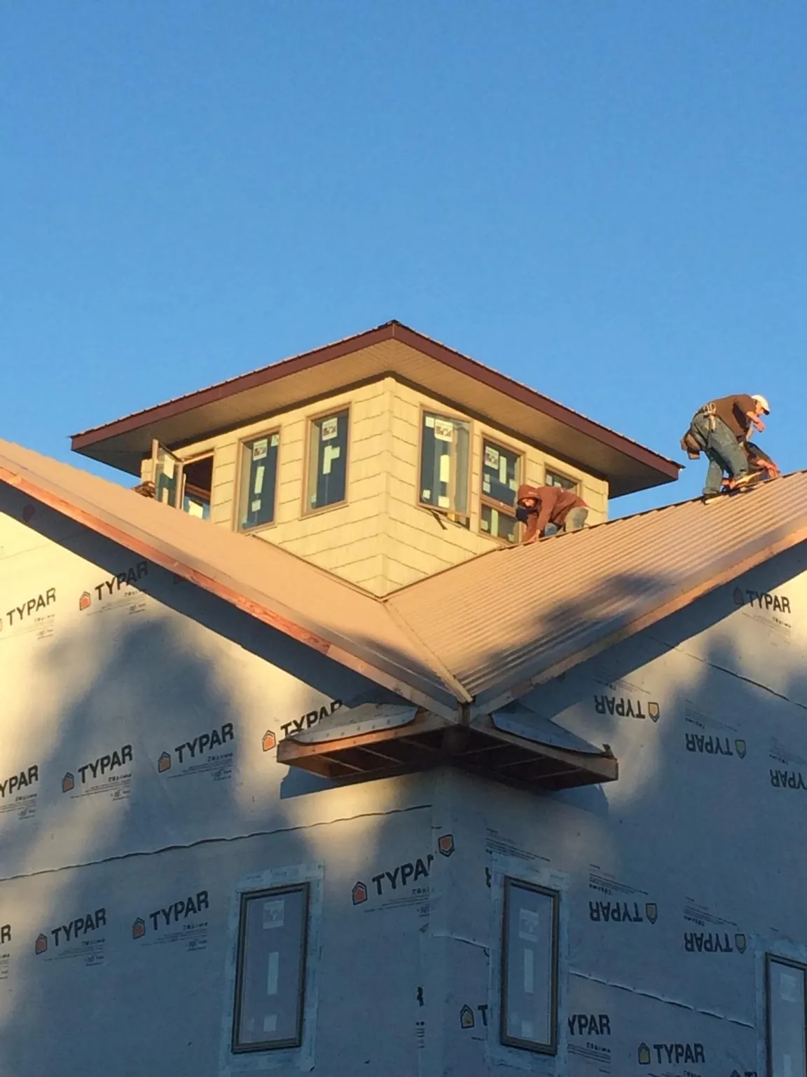 Roofers working around a rooftop cupola on a new metal roof at sunset — Roof Waterproofing in Mckenna by Roofing Brothers